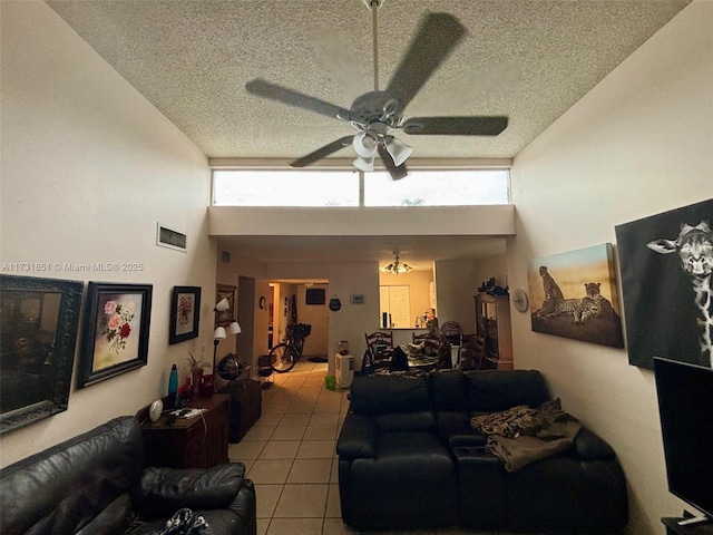 living room with ceiling fan, light tile patterned floors, a textured ceiling, and a high ceiling