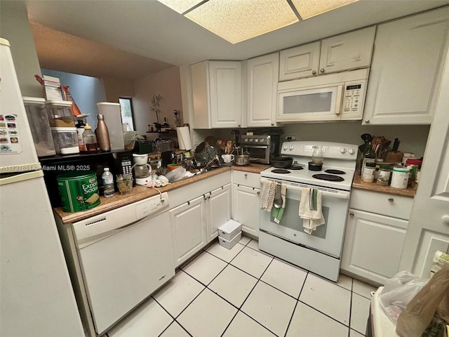 kitchen with light tile patterned floors, white appliances, and white cabinets