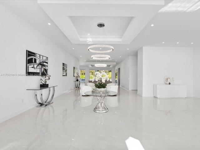 corridor featuring a notable chandelier and a tray ceiling