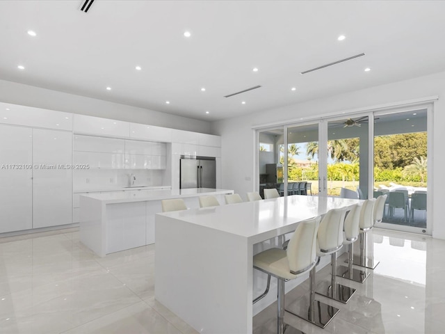 kitchen with high quality fridge, a kitchen breakfast bar, a center island, and white cabinets