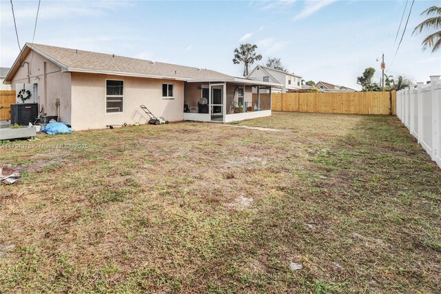 back of house with central AC, a sunroom, and a lawn