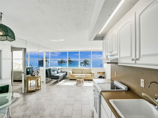 kitchen with white electric range oven, sink, a textured ceiling, and white cabinets