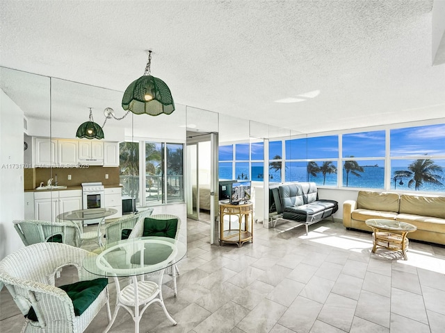 sunroom featuring a water view and sink