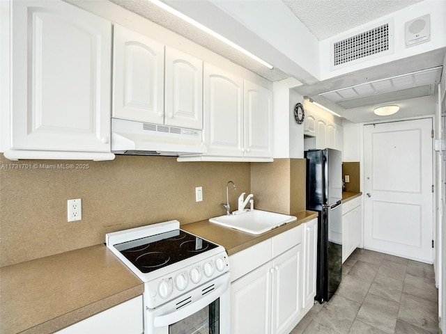 kitchen featuring white electric range, sink, tasteful backsplash, black refrigerator, and white cabinets