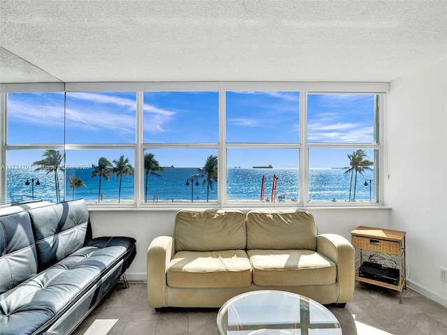 tiled living room with a textured ceiling and a water view