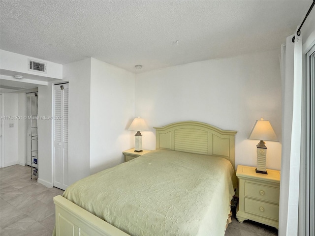 bedroom with multiple closets and a textured ceiling