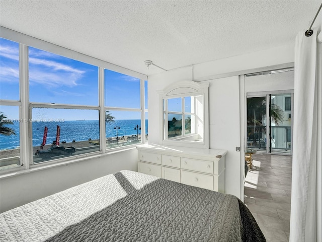 bedroom with a water view and a textured ceiling