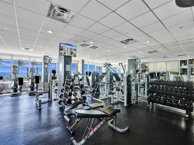 gym with floor to ceiling windows and a drop ceiling