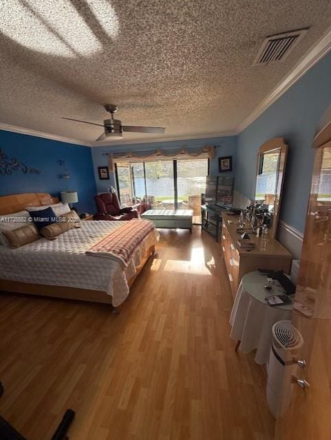 bedroom featuring hardwood / wood-style floors, a textured ceiling, ornamental molding, and ceiling fan