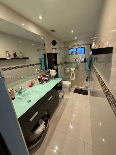 bathroom with backsplash, vanity, toilet, a shower with door, and tile patterned floors