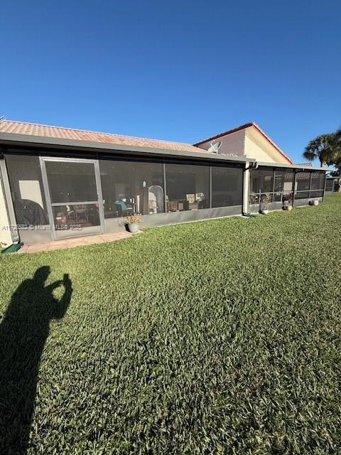 back of property with a yard and a sunroom