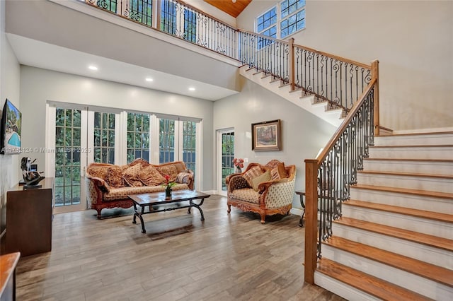 living room featuring a towering ceiling, french doors, and light wood-type flooring