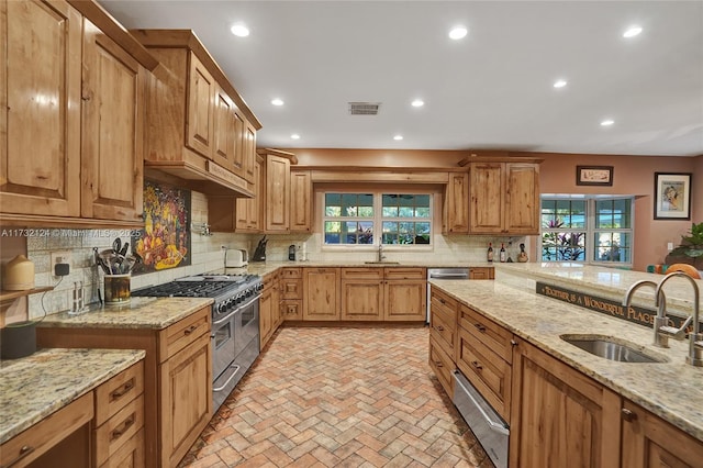 kitchen featuring double oven range, light stone countertops, and sink