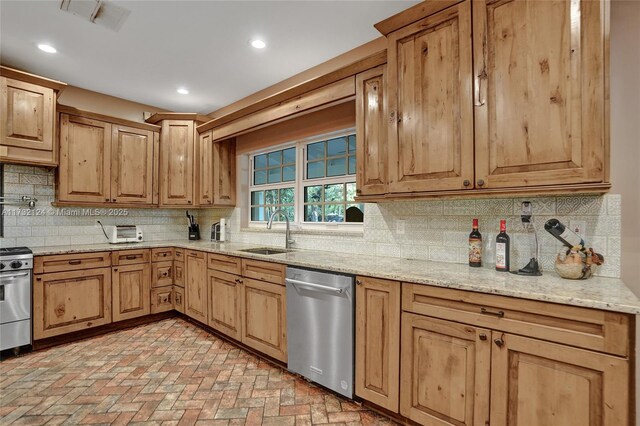 kitchen featuring stainless steel appliances, tasteful backsplash, light stone countertops, and sink