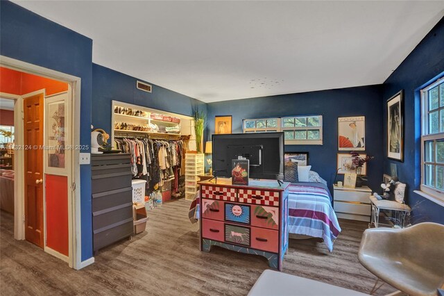 bedroom with hardwood / wood-style flooring, a walk in closet, and a closet