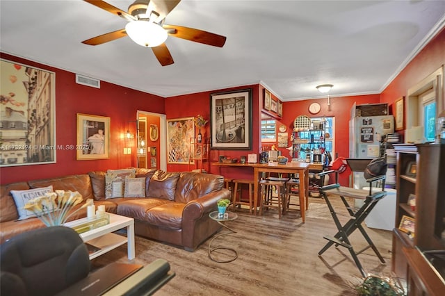 living room with wood-type flooring, ceiling fan, and crown molding