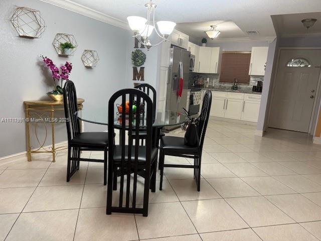 tiled dining area featuring a notable chandelier and ornamental molding