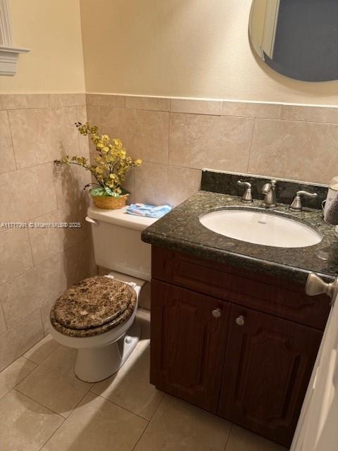 bathroom featuring tile patterned floors, toilet, vanity, and tile walls