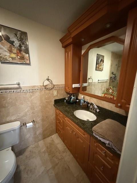 bathroom with vanity, tile walls, and toilet