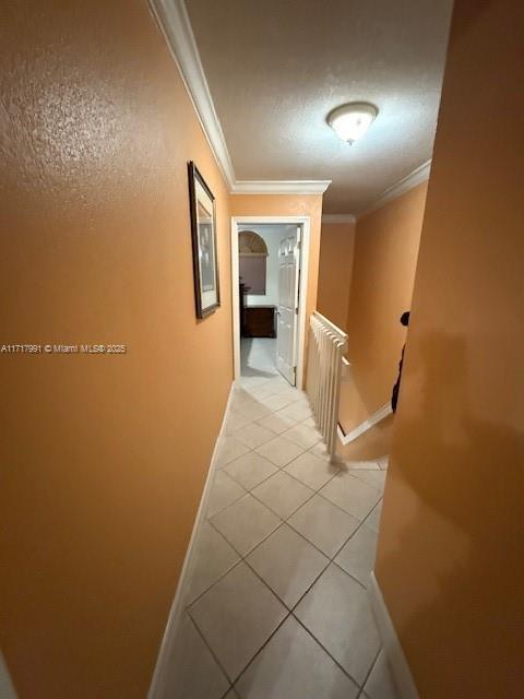 hall featuring ornamental molding and light tile patterned floors