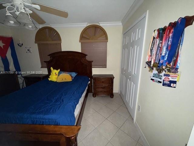 bedroom with tile patterned flooring, crown molding, a closet, and ceiling fan