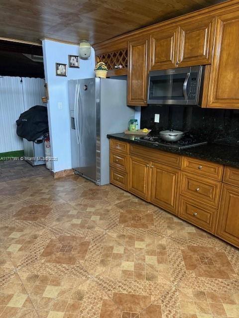 kitchen featuring appliances with stainless steel finishes, dark stone countertops, and decorative backsplash