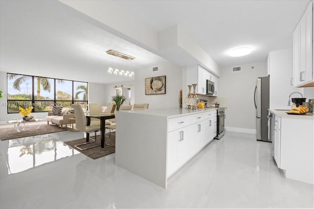 kitchen with white cabinetry, appliances with stainless steel finishes, sink, and decorative light fixtures