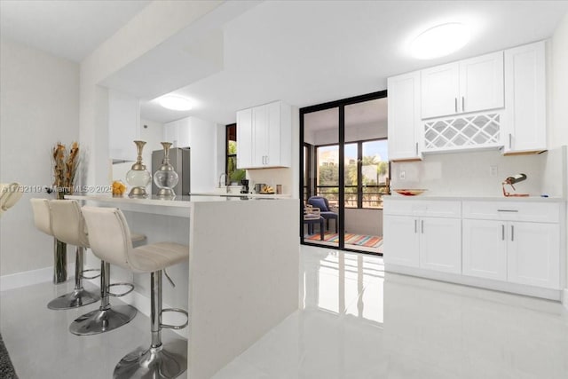 kitchen with expansive windows, white cabinetry, and fridge