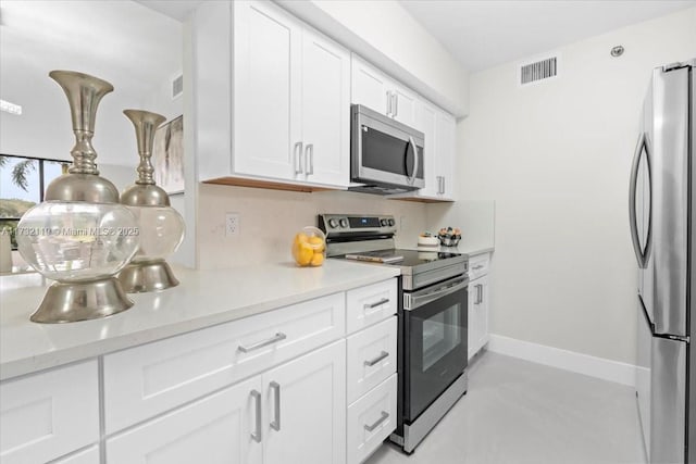 kitchen with appliances with stainless steel finishes, backsplash, white cabinets, and light stone counters