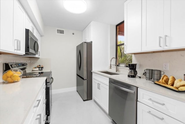 kitchen with light stone counters, appliances with stainless steel finishes, sink, and white cabinets