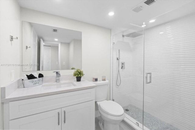 bathroom with vanity, a shower with door, and toilet