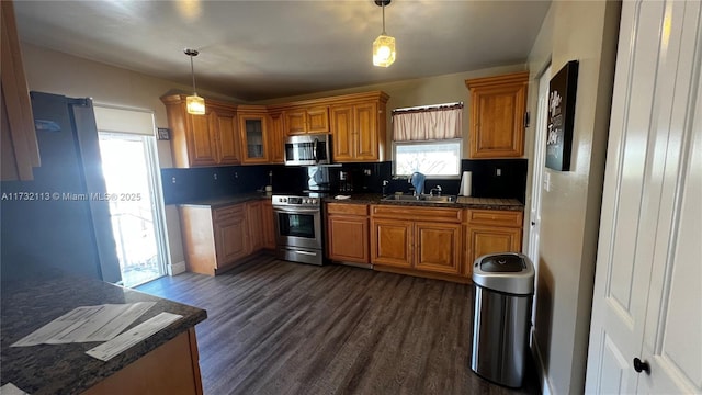 kitchen with hanging light fixtures, tasteful backsplash, appliances with stainless steel finishes, and dark wood-type flooring