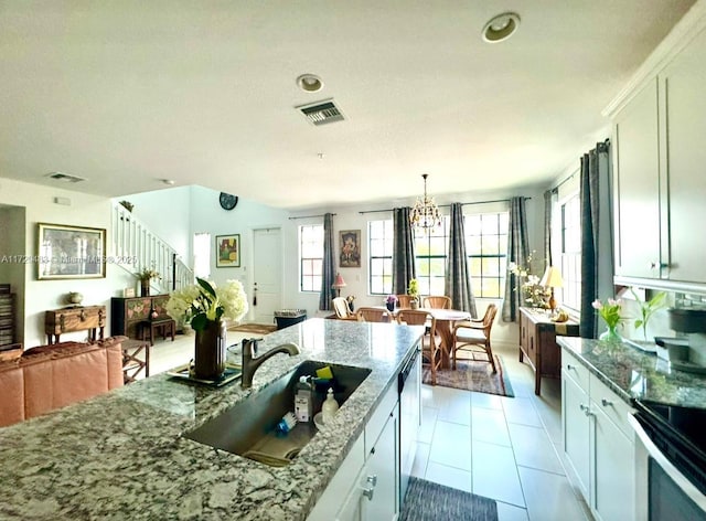 kitchen featuring light tile patterned flooring, pendant lighting, white cabinetry, sink, and light stone counters