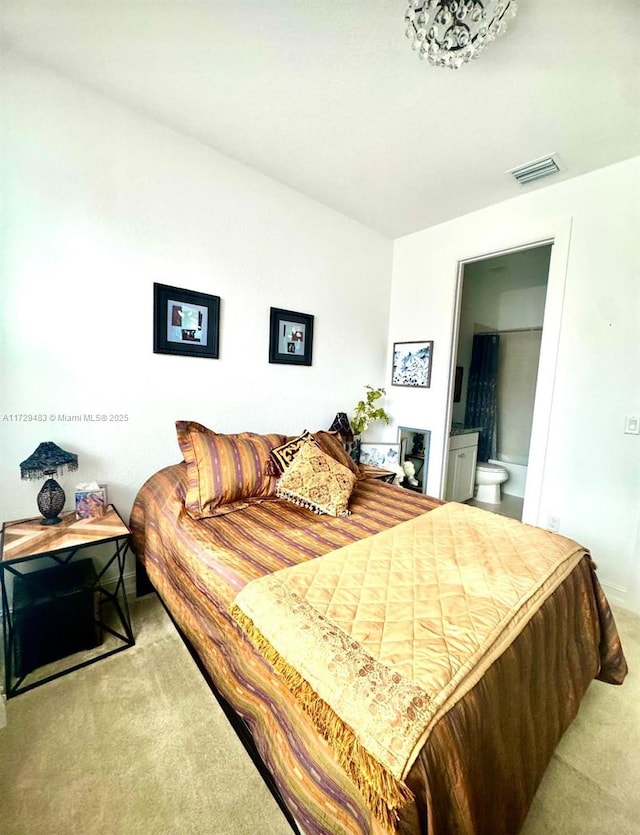 bedroom with ensuite bath and light colored carpet