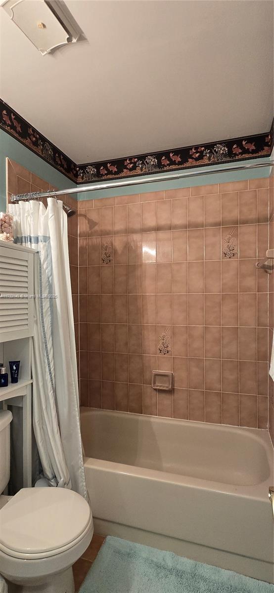 bathroom with tile patterned flooring, shower / bath combo, and toilet