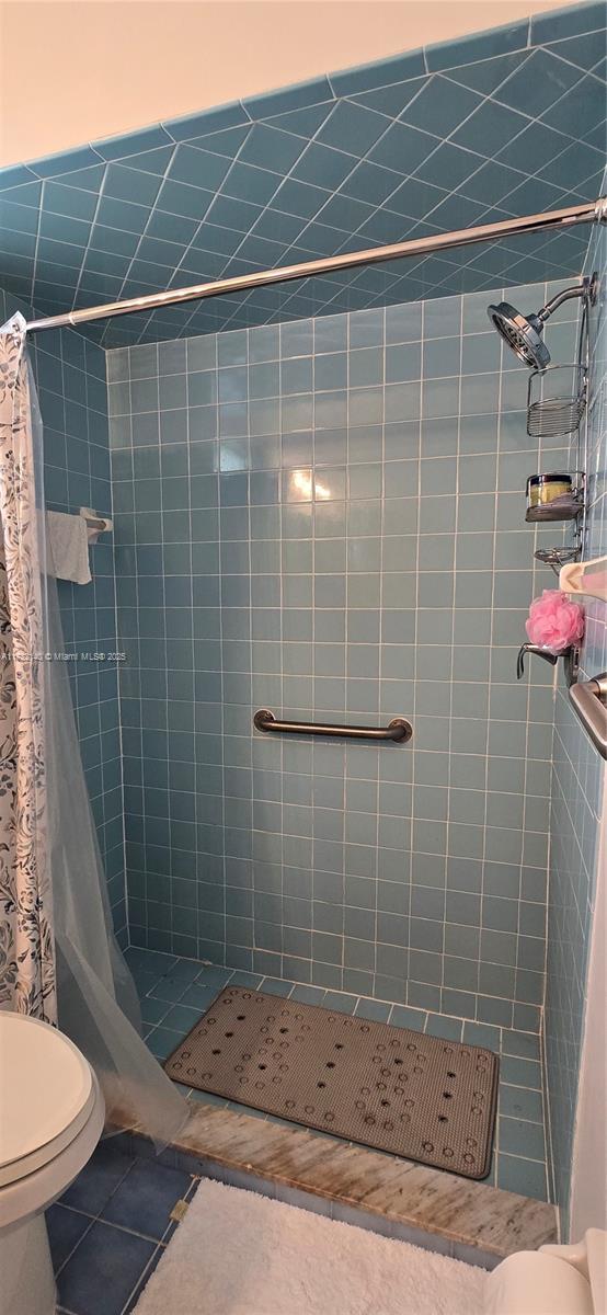 bathroom featuring tile patterned flooring, a shower with curtain, and toilet