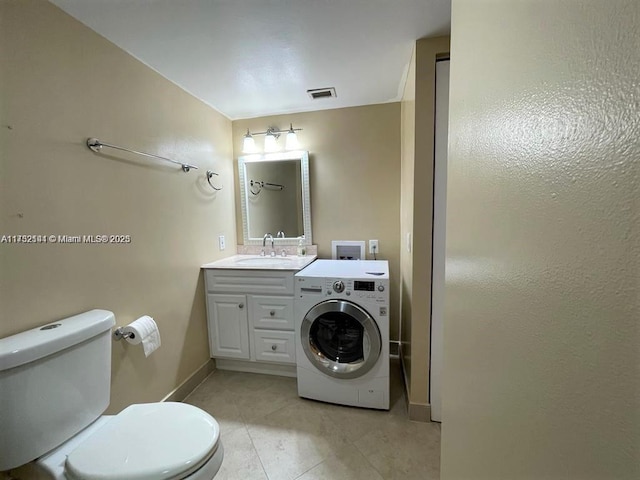 bathroom featuring toilet, vanity, washer / clothes dryer, and tile patterned flooring