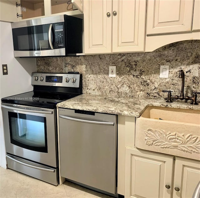 kitchen with light stone counters, stainless steel appliances, decorative backsplash, and light tile patterned floors