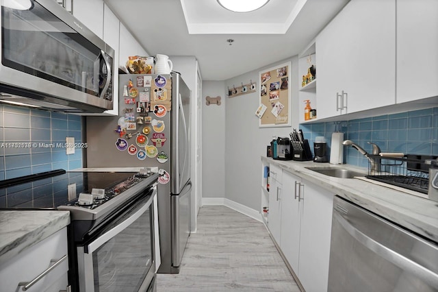 kitchen with backsplash, stainless steel appliances, white cabinets, and light stone countertops