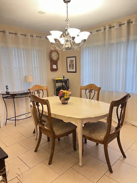 dining space with light tile patterned floors, a chandelier, and a textured ceiling