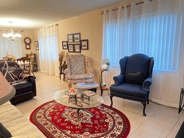 tiled living room with a notable chandelier