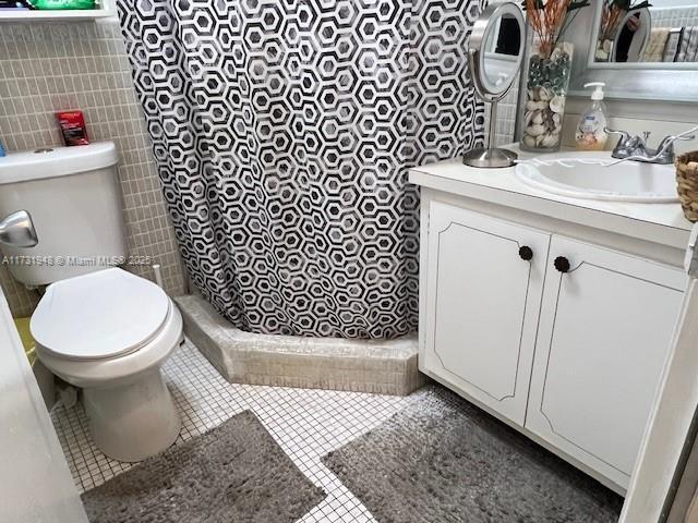 bathroom featuring vanity, curtained shower, tile patterned floors, and toilet