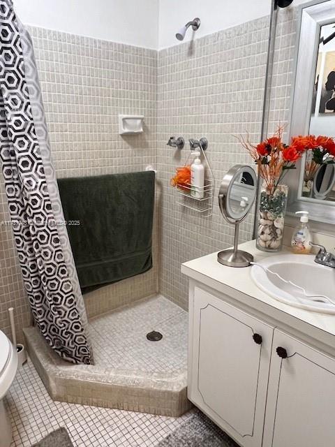 bathroom with vanity, curtained shower, tile patterned floors, and toilet