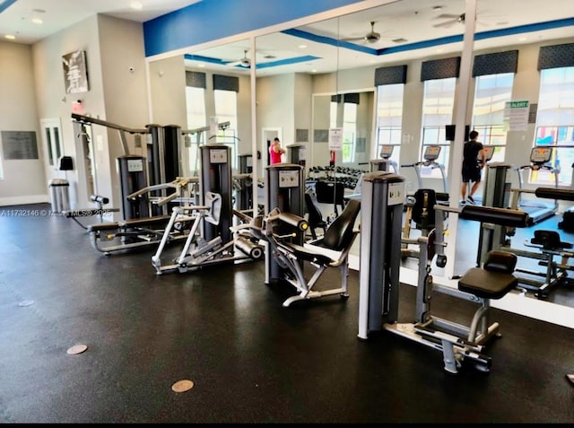 exercise room featuring ceiling fan and a raised ceiling