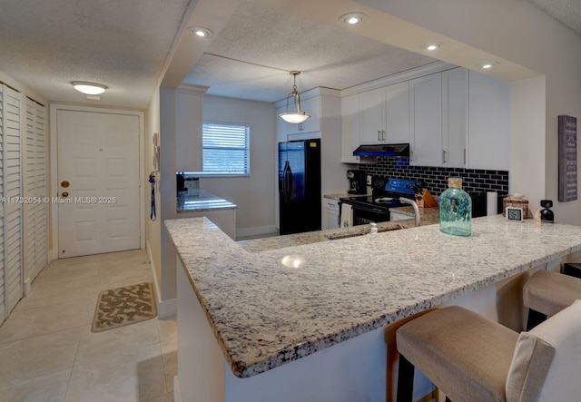 kitchen featuring decorative light fixtures, tasteful backsplash, white cabinetry, black appliances, and kitchen peninsula