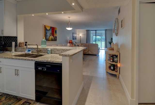 kitchen featuring tasteful backsplash, white cabinetry, dishwasher, sink, and light stone counters