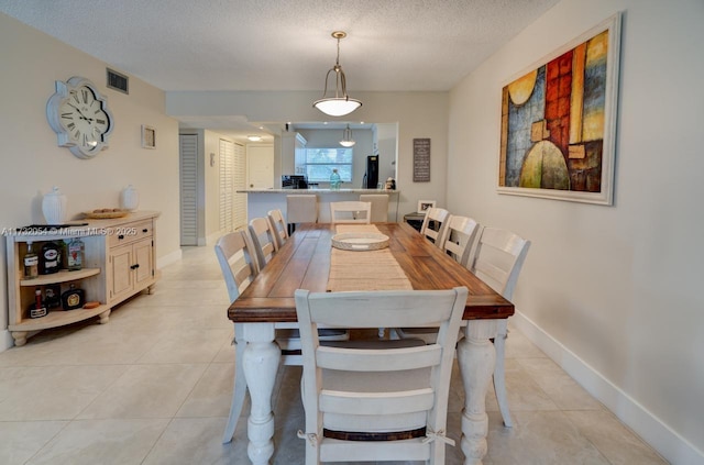 dining area featuring light tile patterned flooring and a textured ceiling