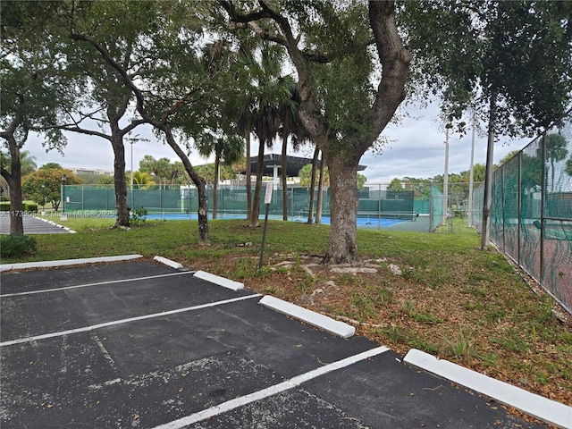 view of car parking featuring tennis court