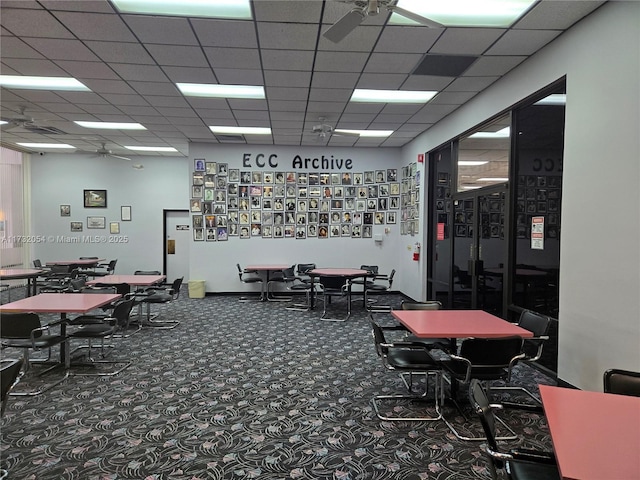 interior space featuring a paneled ceiling, ceiling fan, and carpet flooring