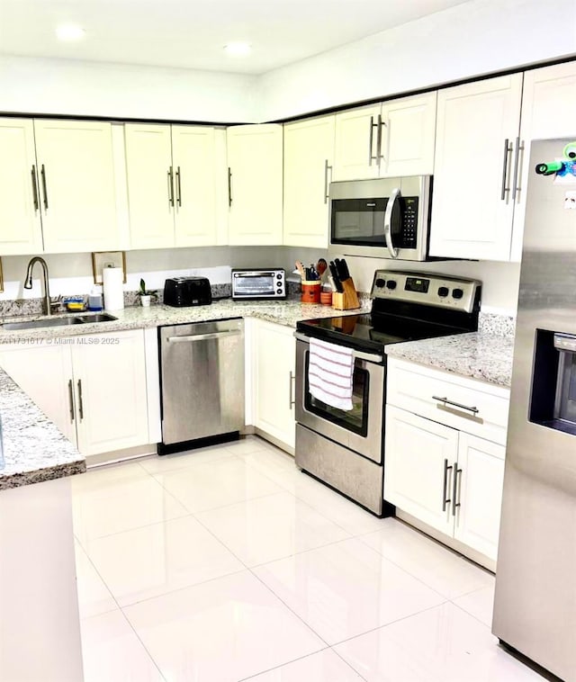 kitchen with white cabinetry, stainless steel appliances, sink, and light tile patterned floors